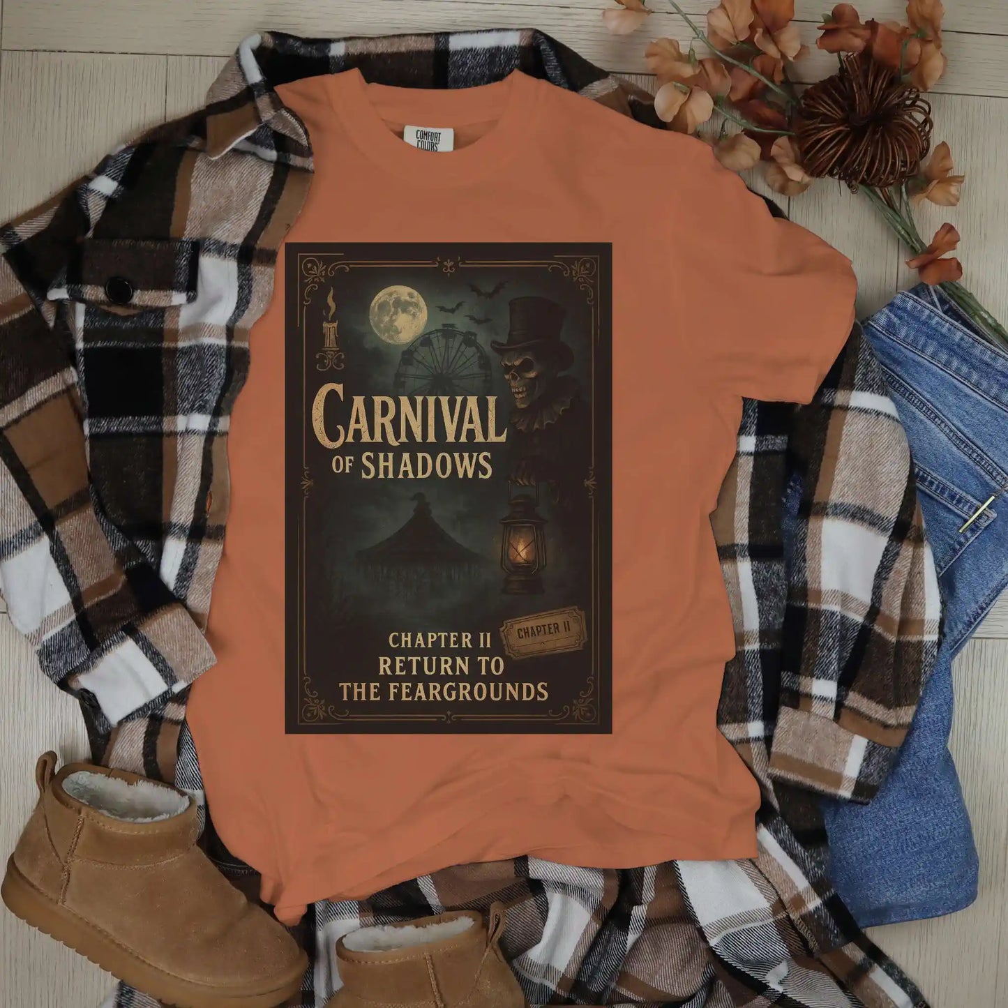 Yam colored t-shirt with 'Carnival of Shadows' design on a plaid shirt and jeans with shoes.