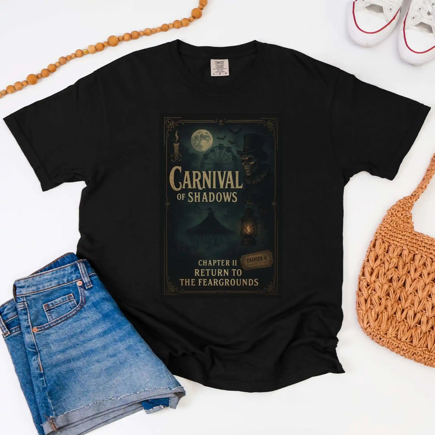 Black t-shirt with 'Carnival of Shadows' design, paired with jeans and a bag on a white background