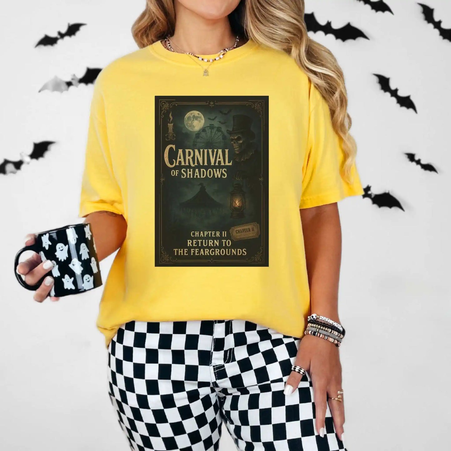 Person wearing a yellow shirt with 'Carnival of Shadows' design, holding a mug with black and white design, against a white background with bats.