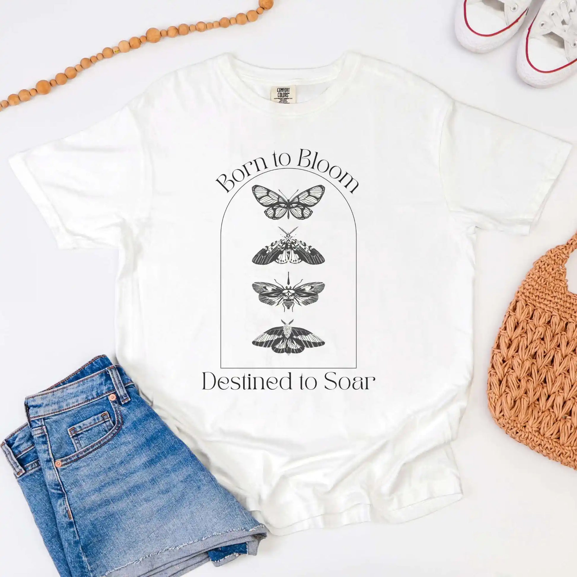 White t-shirt with butterfly design and text 'Born to Bloom, Destined to Soar' on a white background.