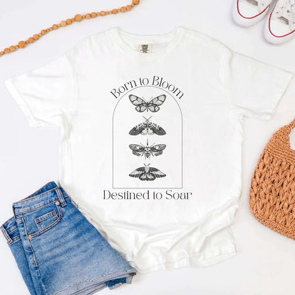 White t-shirt with butterfly design and text 'Born to Bloom, Destined to Soar' on a white background.