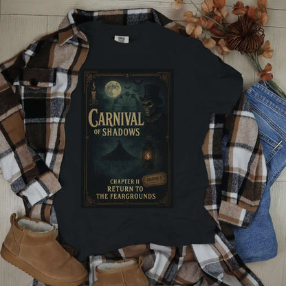 Black t-shirt with 'Carnival of Shadows' design, flannel shirt, jeans, and boots on a wooden surface.