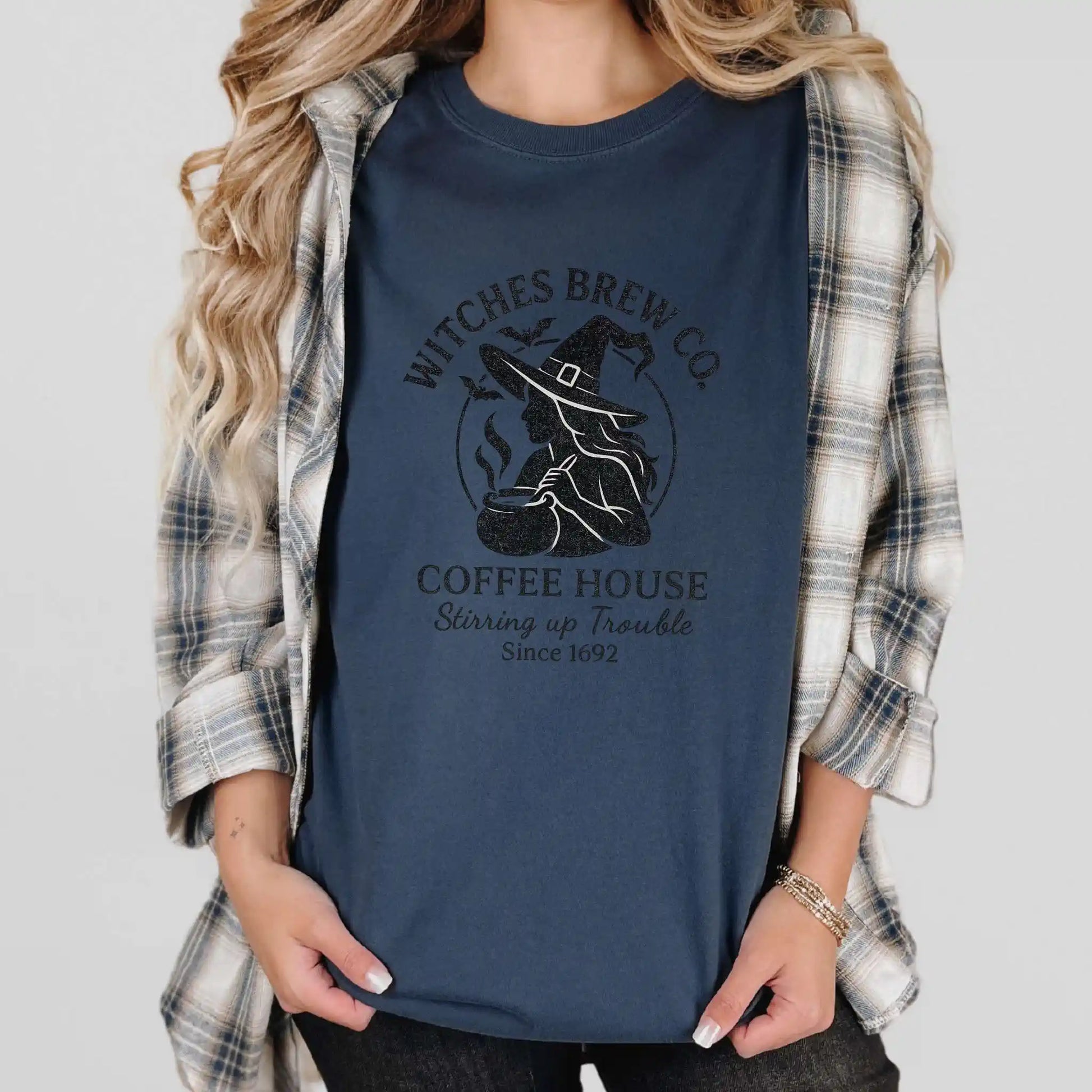 Person wearing a navy blue t-shirt with 'Witches Brew Co. Coffee House' design.