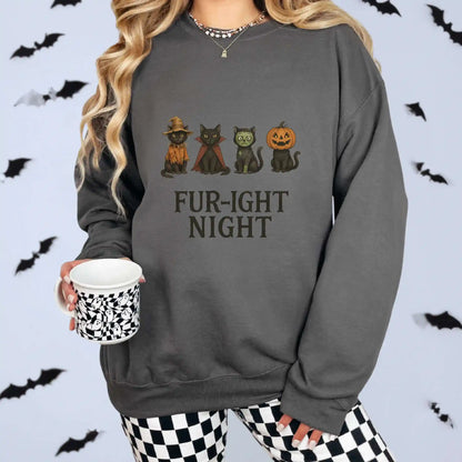 A woman wearing a charcoal sweatshirt with a Halloween-themed design featuring cats in costumes and 'Fur-ight Night' text, with a white background and bat decorations