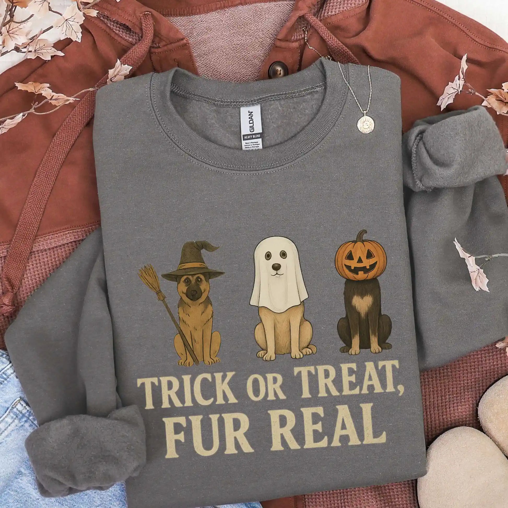 Gray sweatshirt with Halloween-themed design featuring dogs in costumes and text 'Trick or Treat, Fur Real' on a textured surface.