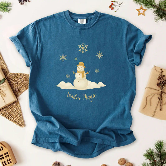 Midnight blue colored t-shirt with a snowman design and 'Winter Magic' text, surrounded by Christmas wrapping and decorations