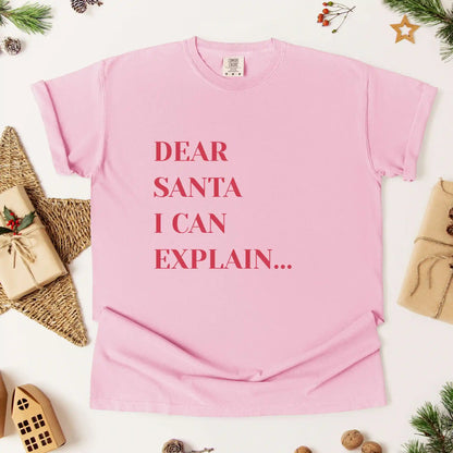 Pink t-shirt with 'Dear Santa I can explain' text on a white background with Christmas decorations.