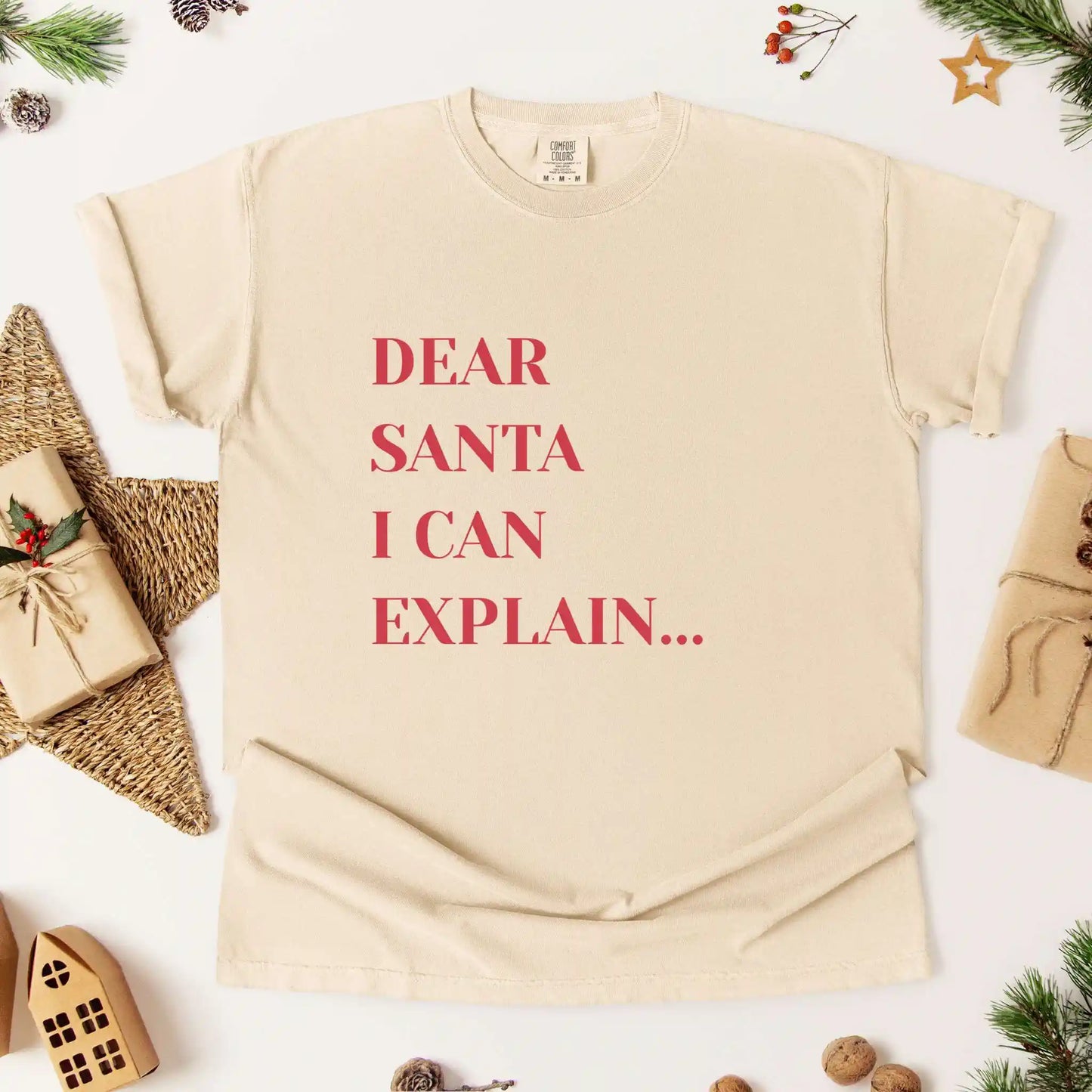 Beige t-shirt with 'Dear Santa I can explain...' text on a white background with Christmas decorations.
